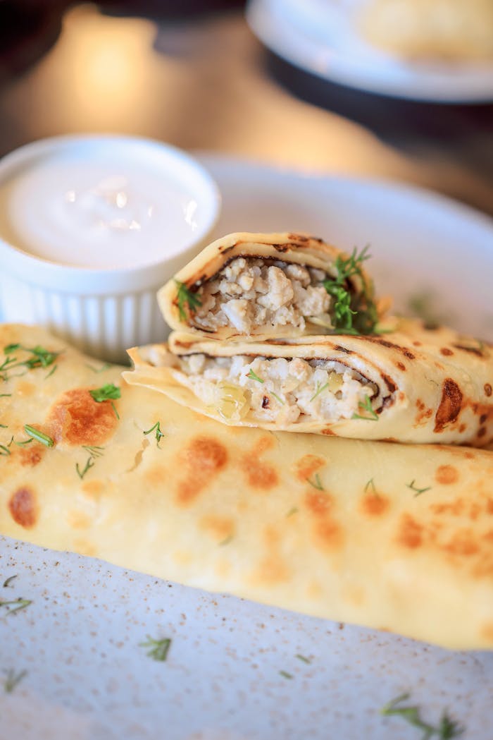 Mouthwatering savory crepes filled with rice and herbs, served with sour cream on the side.